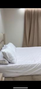 a bed with white sheets and pillows on it at شقه مفروشه in Cairo