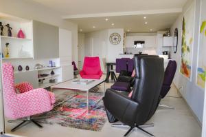 ein Wohnzimmer mit rosa und lila Stühlen und einem Tisch in der Unterkunft Ancora5-Appartement Vue Mer Panoramique et Balcon in La Chaume + 16 Fotos