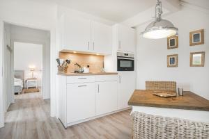a kitchen with white cabinets and a counter top at Ferienwohnung Deichblick Quartier Pellworm in Pellworm +13 photos
