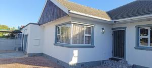 a white house with a window and a door at PEACEFUL SLEEP lodge in Goodwood