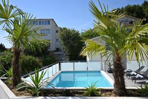 a swimming pool with two palm trees and a building at Luxury Apartment Antoni in Podstrana