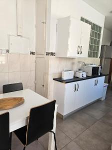 a kitchen with white cabinets and a table with chairs at Lagos Haven Guesthouse in Lagos