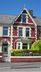 a red brick house with a white door at Ty Rosa Rooms in Cardiff