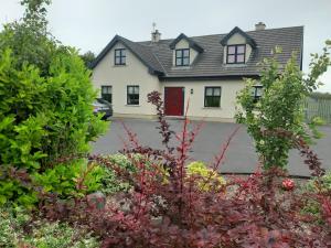 a large white house with a red door at Aira Lodge Accommodation in Kinvara