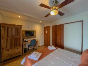 a bedroom with a bed with a ceiling fan and a desk at Casa Melville Hospedagem - Sua Casa de Alto Padrão no Coração de Ubatuba! in Ubatuba