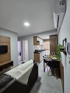 a living room with a table and a kitchen at Apartamento inteiro, ar-condicionado e vaga de garagem in Paranaguá