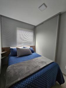 a bedroom with a bed with blue sheets and a window at Apartamento inteiro, ar-condicionado e vaga de garagem in Paranaguá