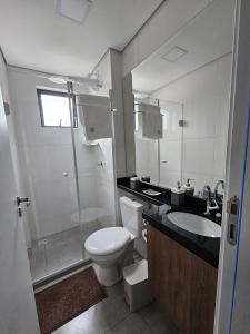 a bathroom with a toilet and a sink and a shower at Apartamento inteiro, ar-condicionado e vaga de garagem in Paranaguá