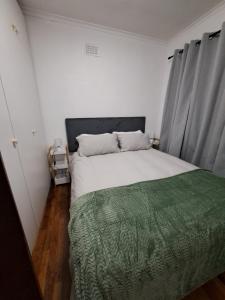 a bedroom with a large bed with a green blanket at Azzure Apartments 6 sleeper Crawford in Cape Town