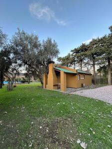 a small yellow house in a field with trees at Cabañas Ojo de Agua in Sierra de la Ventana