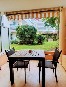 Appartement cosy piscine plage 2 pièces في فريجوس: طاولة وكراسي خشبية على فناء مع نافذة