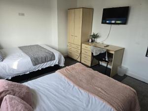 a bedroom with two beds and a desk with a television at Room 5 Shared House in L7 in Liverpool