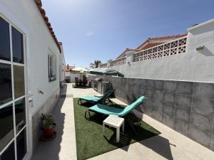 a patio with two chaise lounges and a fence at Villa Stay & Enjoy in Antigua