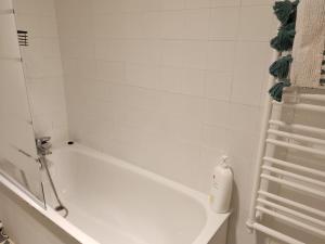 a white bathroom with a bath tub and a shower at L'Escali'Bulle - Entre Gare et Centre-ville in La Celle-sous-Gouzon