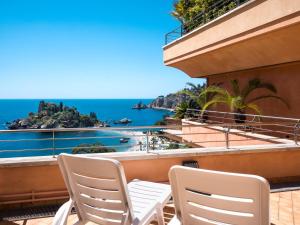 a balcony with chairs and a view of the ocean at Taormina Panoramic Hotel in Taormina