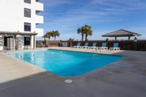 a swimming pool with chairs and a building at 0210 Sun-Kissed Memories condo in Carolina Beach