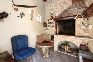 a living room with a stone fireplace and a blue chair at Radovčić Apartments and Rooms in Trsteno