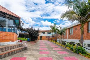 a walkway in front of a building with palm trees at Hotel Centro Recreacional Villa El Encanto in Belén