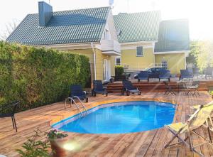 a pool on a deck with chairs and a house at V36 Žemutinė studija in Palanga