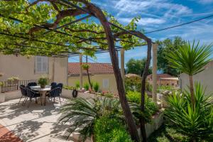 a patio with a table and chairs and plants at Radovčić Apartments and Rooms in Trsteno