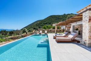 a swimming pool with lounge chairs and a villa at Calliste Villa in Évyiros