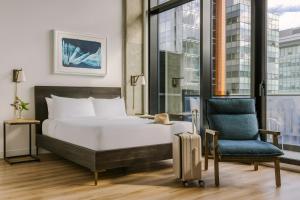 a bedroom with a bed and a chair and a suitcase at Hôtel Monroe - Downtown Montreal in Montreal