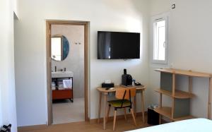 ein Zimmer mit einem Schreibtisch und einem Fernseher an der Wand in der Unterkunft Hotel Le Kallisté in Hyères