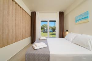 a bedroom with a large bed and a window at Kalliston Beach Apartments in Limenas