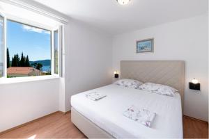 a white bedroom with a white bed and a window at Radovčić Apartments and Rooms in Trsteno