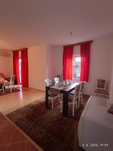 a dining room with a table and red curtains at Apartman ASI in Mostar