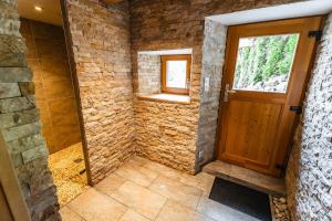ein Bad aus Stein mit einer Holztür und einem Fenster in der Unterkunft Aux Sources - 14 personnes - sauna & jacuzzi in La Bresse
