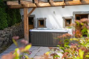 einen Whirlpool im Freien in einem Garten neben einem Gebäude in der Unterkunft Aux Sources - 14 personnes - sauna & jacuzzi in La Bresse