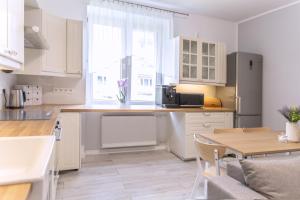 a kitchen with white cabinets and a wooden table at Baltic Cliff Apartment- Babie Doły in Gdynia