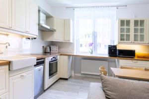 a kitchen with white cabinets and a sink and a table at Baltic Cliff Apartment- Babie Doły in Gdynia