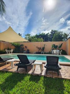 a swimming pool with two chairs and a tent at Coral Island Suites Cozumel in Cozumel