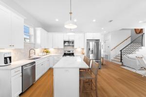 a white kitchen with white cabinets and a kitchen island at The Bungalow by Travel Life Vacations in Destin