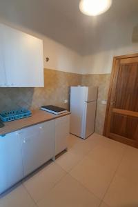 a kitchen with white cabinets and a white refrigerator at Bilocale Su Lizzu de Erminia in La Caletta