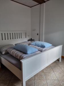 a white bed with two blue pillows on it at Ferienwohnung zur Töpferstube 2 - 2025 in Spabrücken