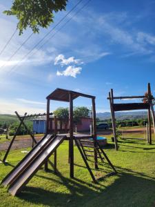 a playground with a slide in the grass at Pousada Casa do Campo Zelito in Delfinópolis