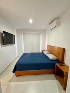 ein Schlafzimmer mit einem blauen Bett und einem TV in der Unterkunft LOFT NUEVO ! En Cerritos OCEANNA frente al MAR ! - 237 B - in Mazatlán