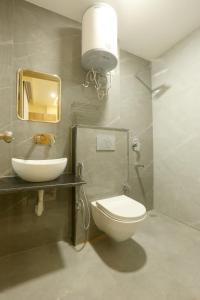 新德里Hotel Lyf Corporate Suites In Mahipalpur Near IGI Airport的浴室里有洗手池、马桶和镜子。 更多19张照片