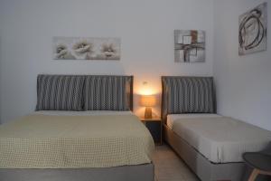 sypialnia z 2 łóżkami, stołem i lampką w obiekcie Seafront Studio w mieście Cherronisos