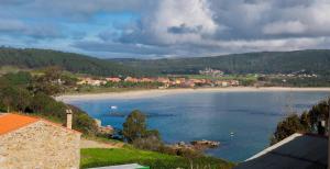 a view of a beach with houses in the distance at Albergue Oceanus Finisterre in Finisterre