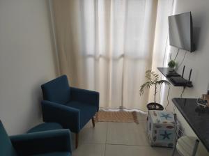 a living room with a blue chair and a television at Apt no Santa Mônica próximo ao Pátio Sabiá, UFU in Uberlândia