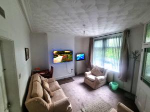 a living room with a couch and a tv at 4 Bedroom Spacious House Perfect for Family & Business Short Long-Term Stays Easy Access to Manchester, Oldham, Bury in Rochdale