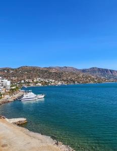 a boat in the water next to a beach at Costalia Seafront Apt in Elounda