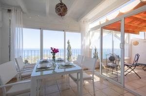 a dining room with a white table and white chairs at Vista Divina in Cumbre del Sol