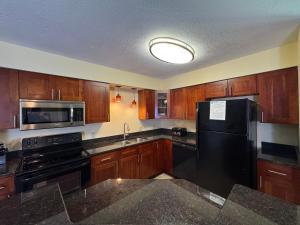 a kitchen with wooden cabinets and a black refrigerator at Put-in-Bay Poolview Condo #5 in Put-in-Bay +19 photos