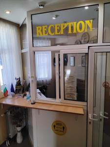 a reception desk in an office with a reflection in the window at Hotel Mehdjarel in Shumen