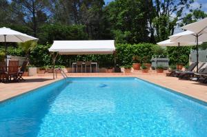 a swimming pool with an umbrella and a table and chairs at La Bégude Du Pascouren in Fayence